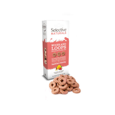 A box of Selective Naturals Woodland Loops, a snack for guinea pigs, in dandelion and rosehip flavor. The packaging is white and red, featuring silhouettes of small animals and key product benefits. In front of the box, several reddish-brown, ring-shaped treats are displayed.