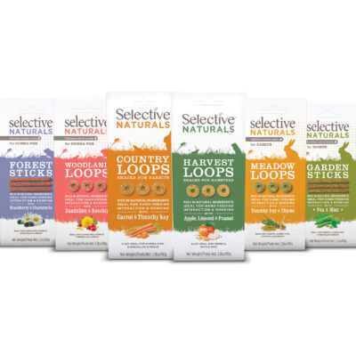 Selection of Selective Naturals treats for small pets, including Forest Sticks, Woodland Loops, Country Loops, Harvest Loops, Meadow Loops, and Garden Sticks, each with natural ingredients for guinea pigs, rabbits, hamsters, and other small animals. The treats are packaged in colorful bags, highlighting flavors like Blackberry & Chamomile, Dandelion & Rosehip, Carrot & Timothy Hay, Apple, Linseed & Peanut, Timothy Hay & Thyme, and Pea & Mint.